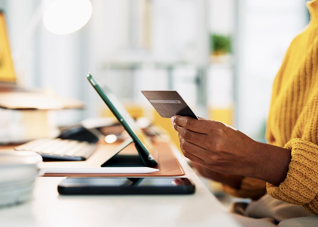 A businesswoman holding up a credit card while at work in the office.