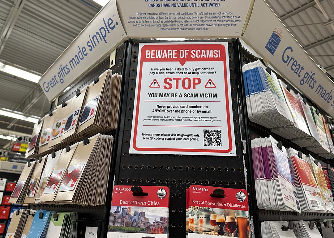 A large 'beware of scams' sign on display at a gift card aisle in a store.