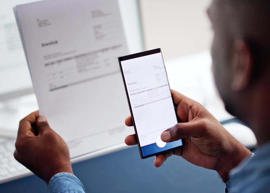 A man taking a photo of an invoice document using a phone.