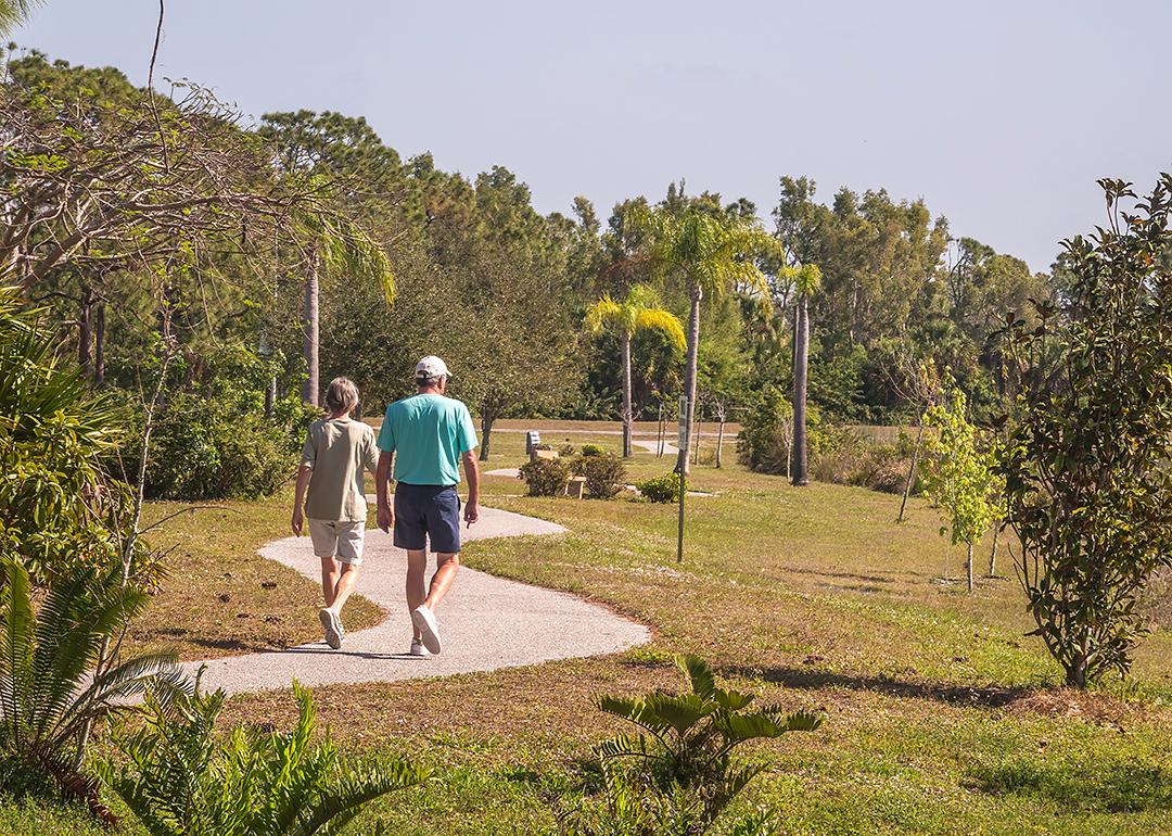 Two seniors walking a trail at a park during spring time.