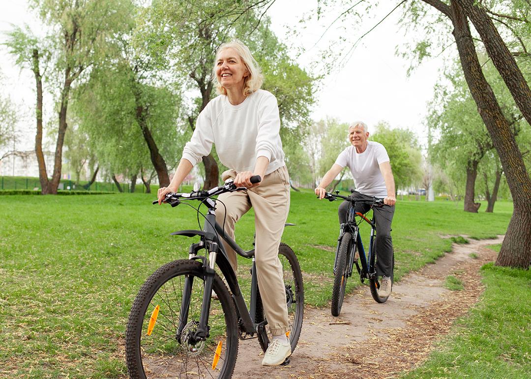 A senior couple riding bikes in a park.
