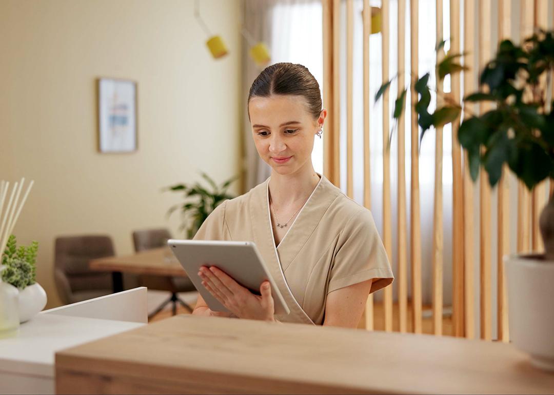 A female front desk staff at a spa using a digital tablet to look at schedule.