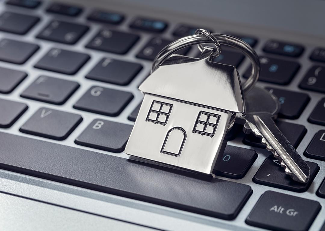 A house key and steel house keychain on top of a laptop keyboard.