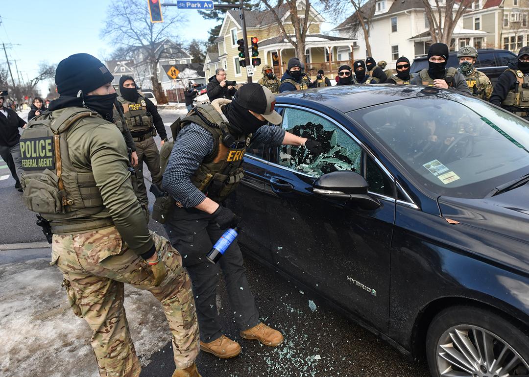 ICE officers breaking a car window to remove a woman from her vehicle on January 13, 2026 in Minneapolis, Minnesota.