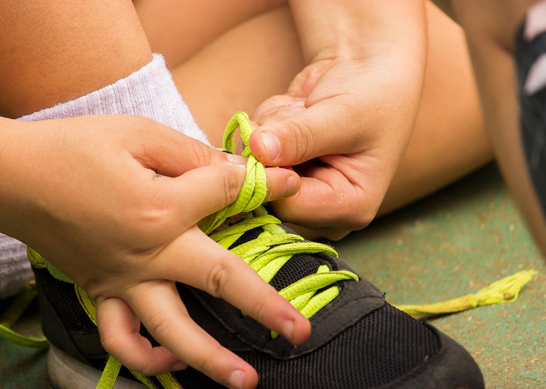 A young boy's hands tying shoelaces by himself.