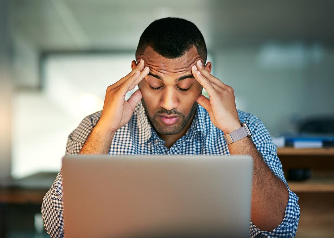 A stressed businessman facing a laptop.