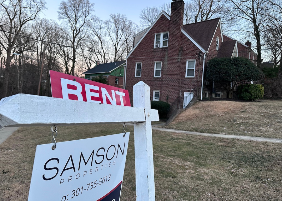 A sign in foreground lists a home for rent in Maryland with tall brick home in the background. Municipal rental registries are gaining attention as cities try to get a handle on who owns rental properties and where, both to better understand their housing landscape and to ensure rentals are safe for tenants. 
