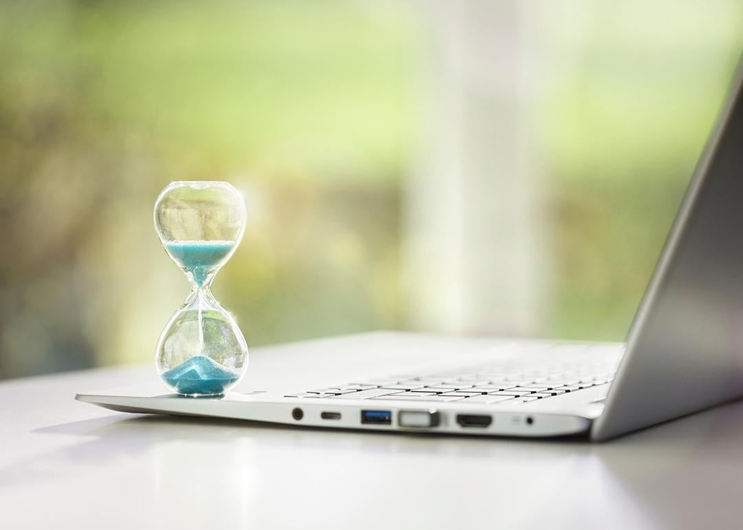 A small hourglass on top of a laptop as a concept of deadline and time management.