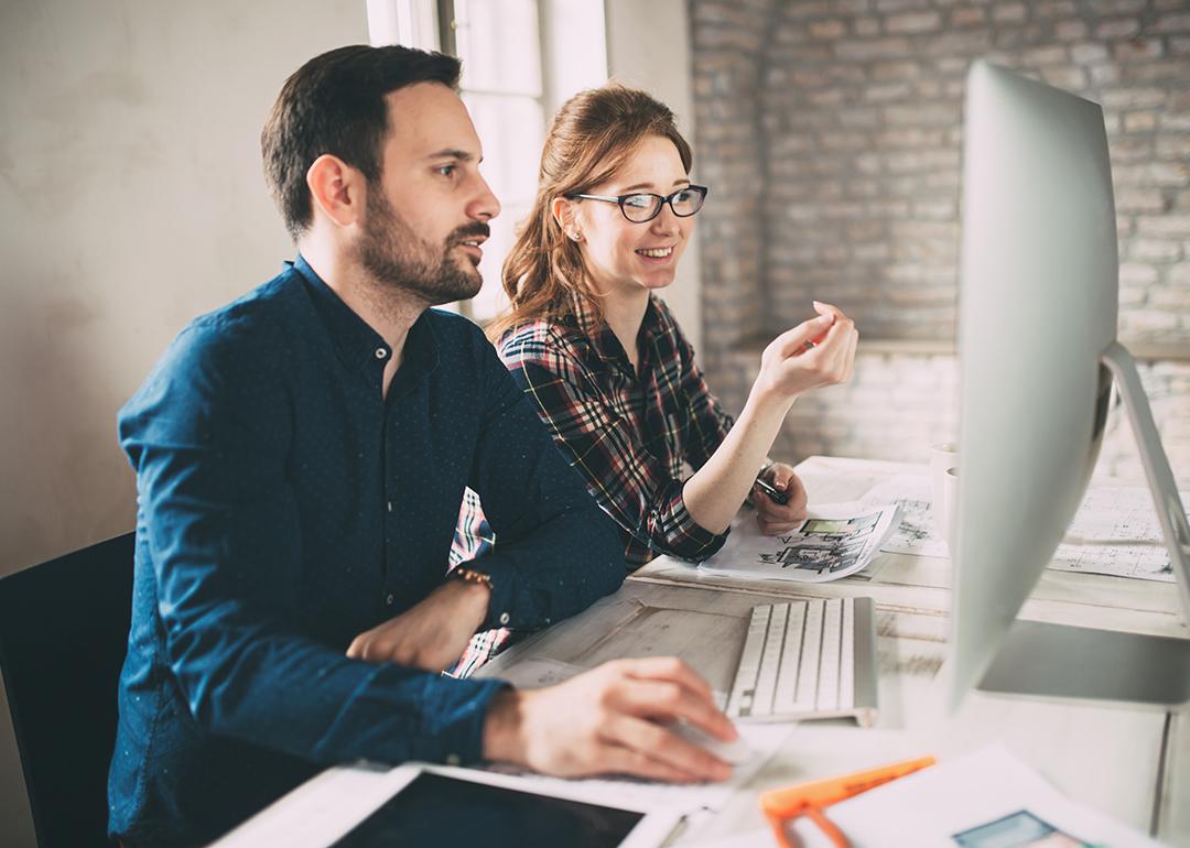 Two colleagues working in front of a computer monitor in an office.