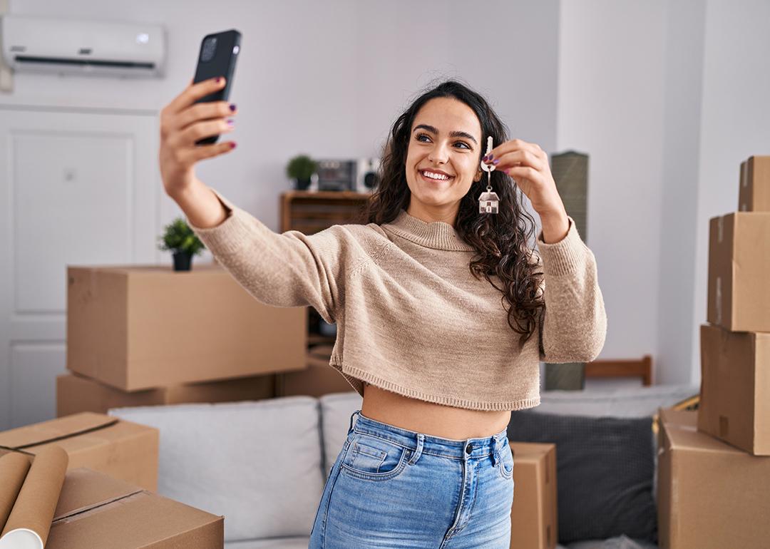 A young woman taking a selfie with her new home's keys.