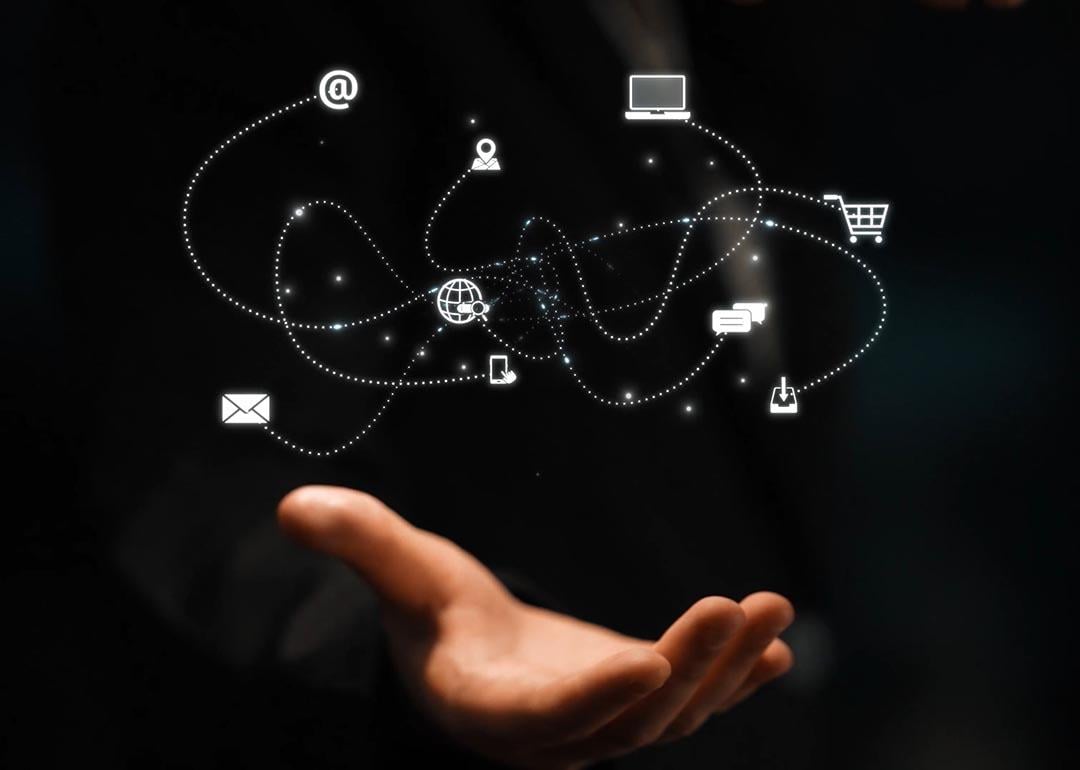 A network of marketing and communication concept icons over a person's hand.