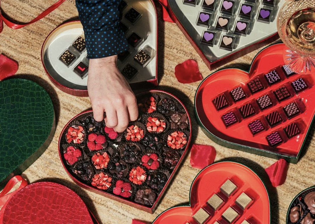 Person picking from a heart-shaped box of chocolates.