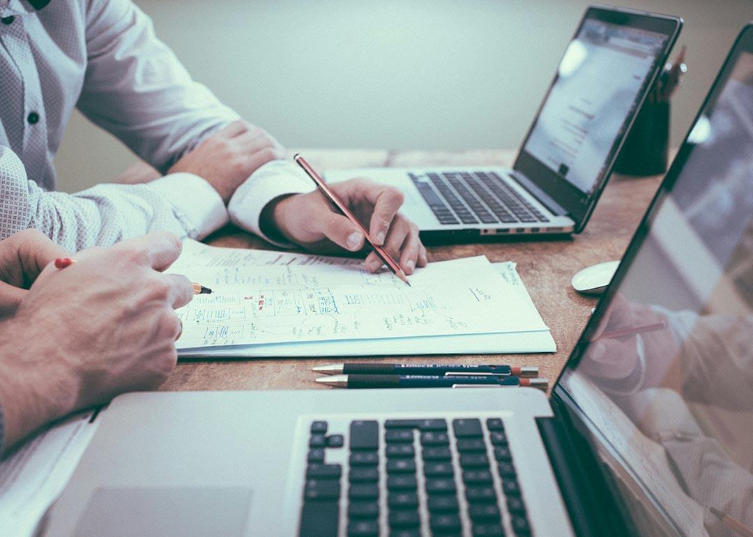 Businesspeople planning on paper in front of their laptop.s