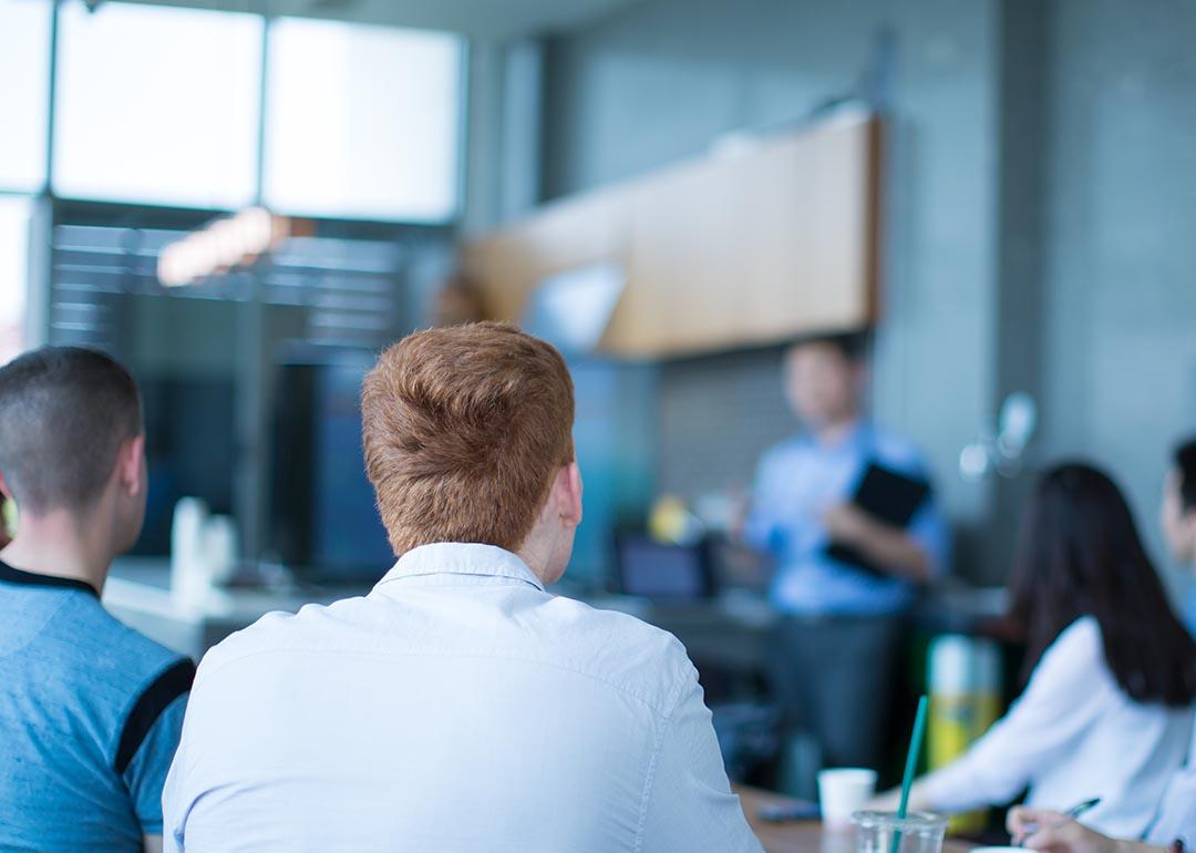 A sales team listening to a presenter in the office.