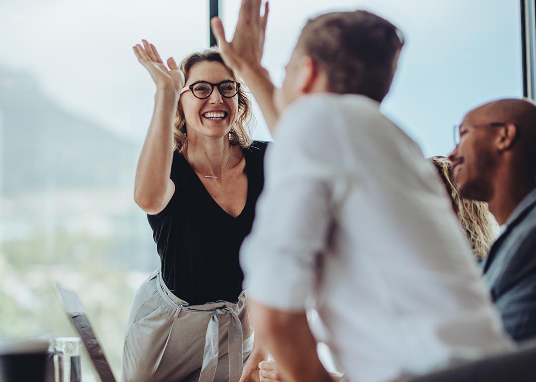 A businesswoman getting a high-five from a colleague.
