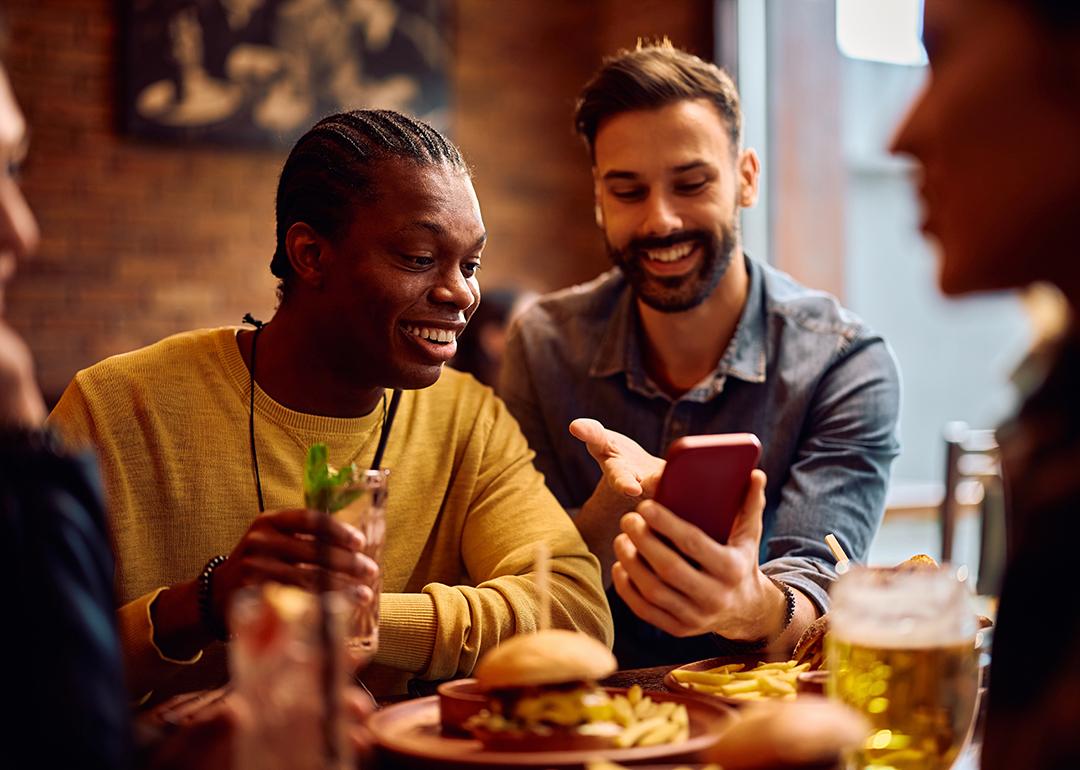 Happy men looking on their phones while sitting in a bar.