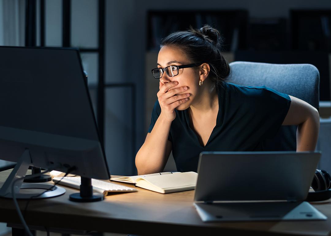 A female employee shocked in front of a computer seeing data hacked.