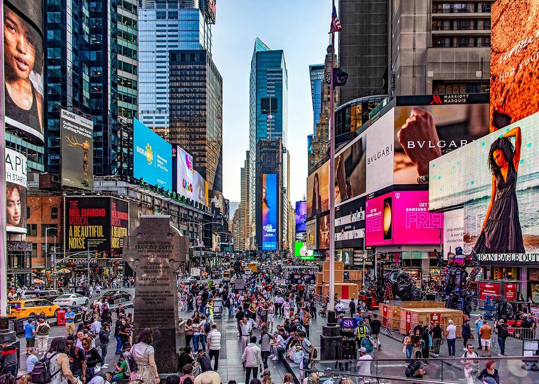 Crowds of people and lit up billboards around Times Square in New York City. 