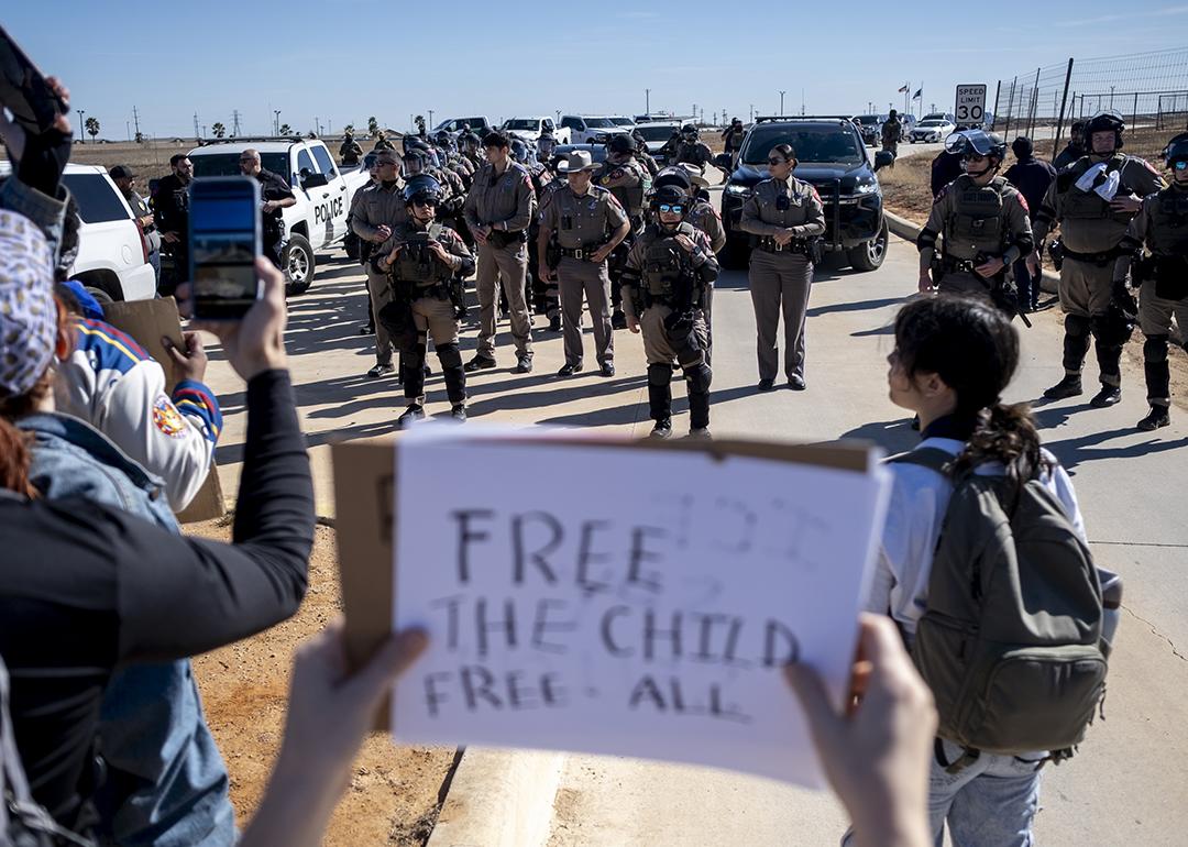 Texas State Troopers surrounded by protesters as they denounce detention of 5-year-old, Liam Ramos, at an immigration processing facility in Texas. One person holding a 'free the child, free all' sign put it up facing the troopers.
