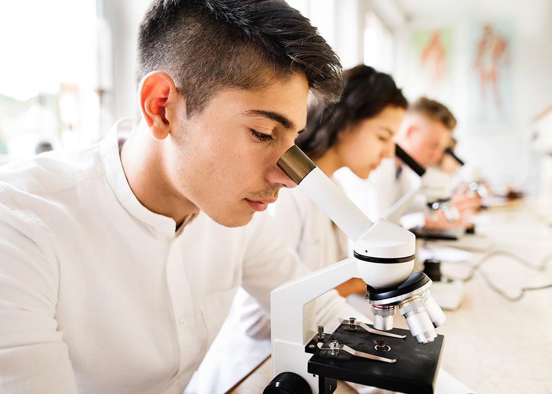 High school students working with microscopes in a laboratory.