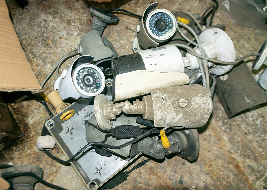 Assorted old and dusty surveillance cameras and electronic parts.