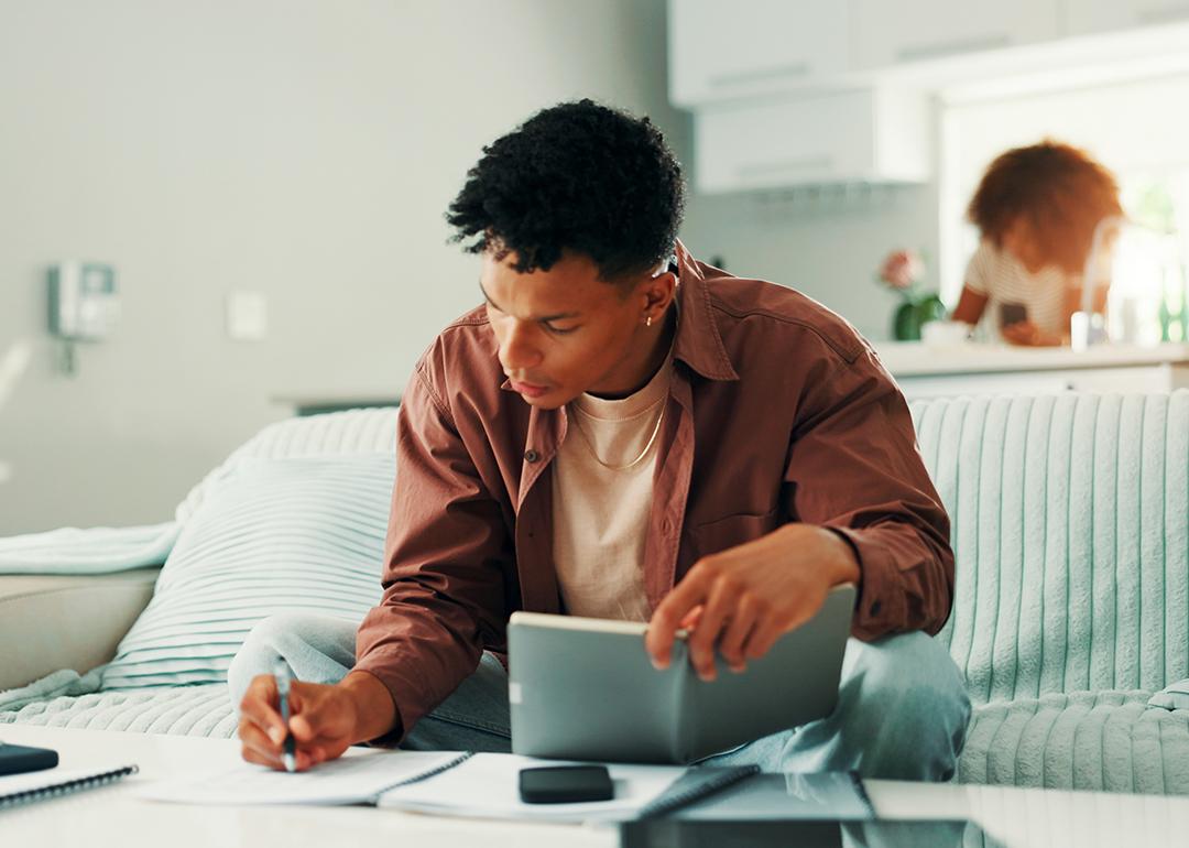 Young man noting expenses and managing finances at home.
