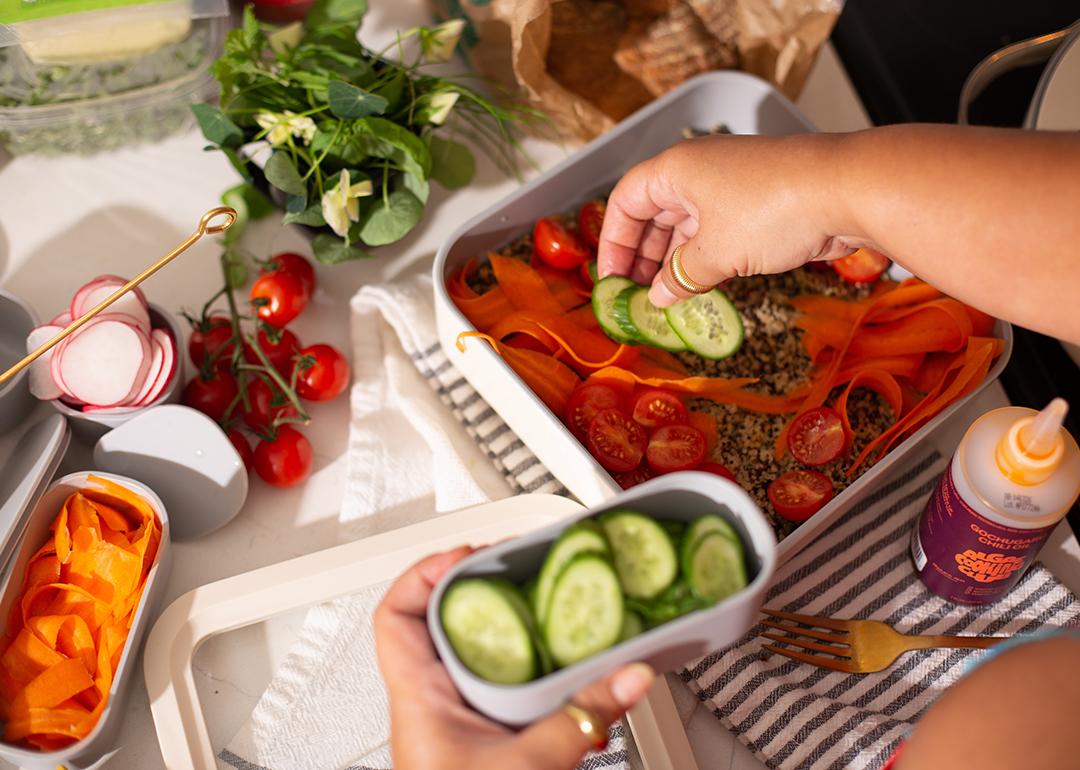 Vegetables being added on top of a healthy meal prep dish.