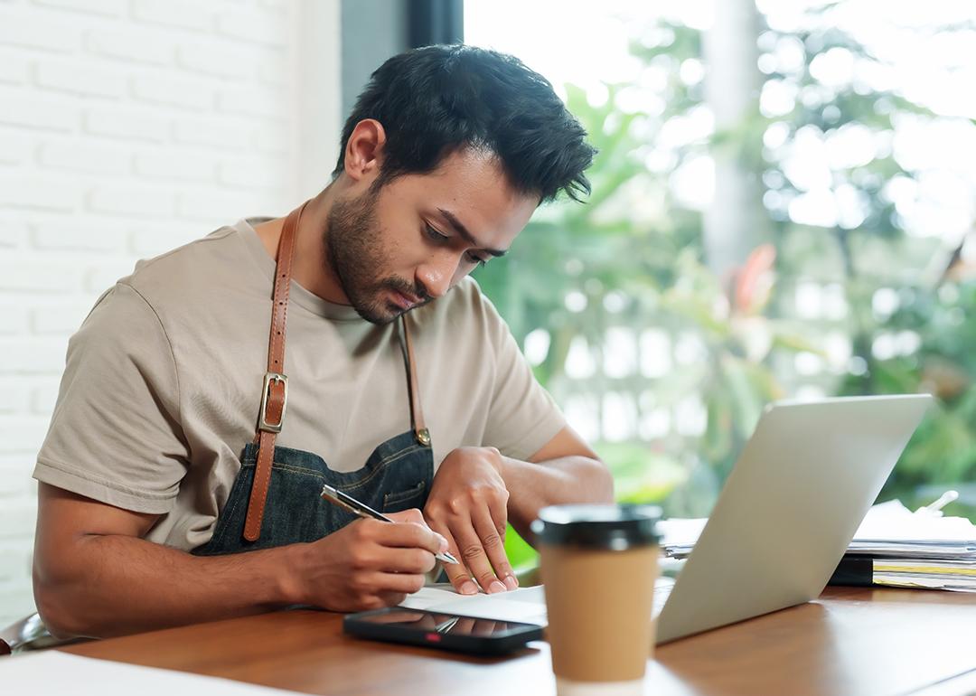 A young small cafe business owner reviewing reports at a cafe desk.