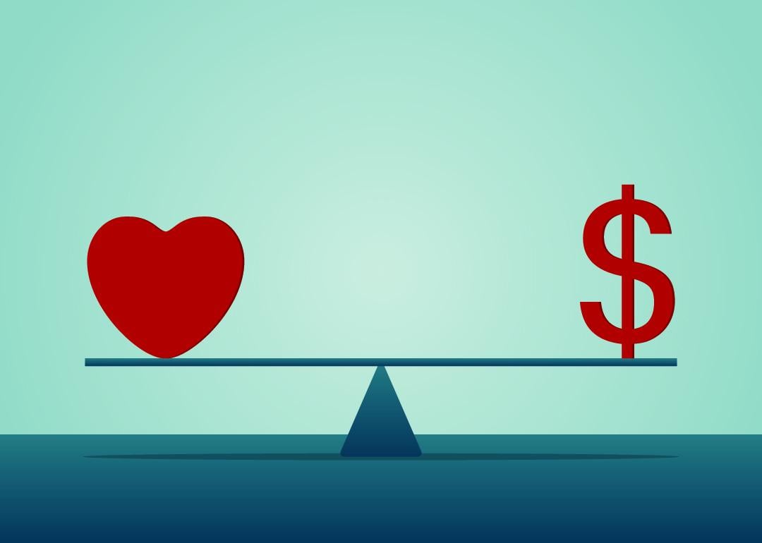A heart and a dollar symbol on both ends of a seesaw.