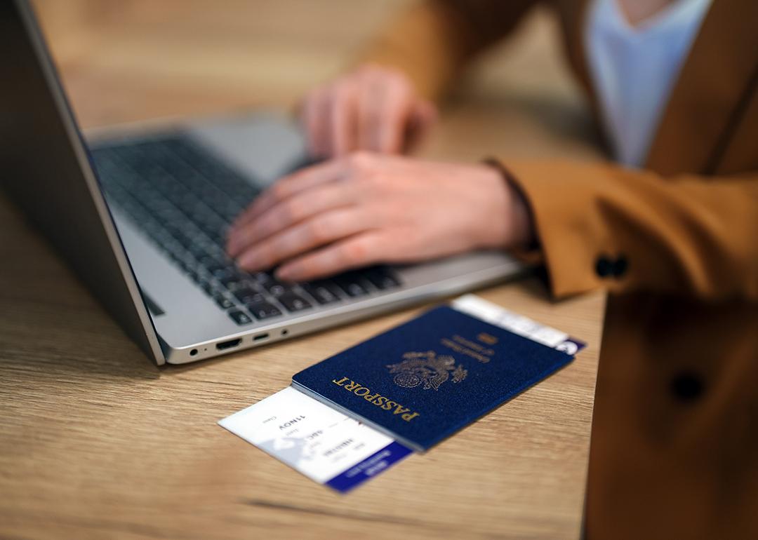 Female traveler using laptop with passport ready at the side while waiting for her flight.