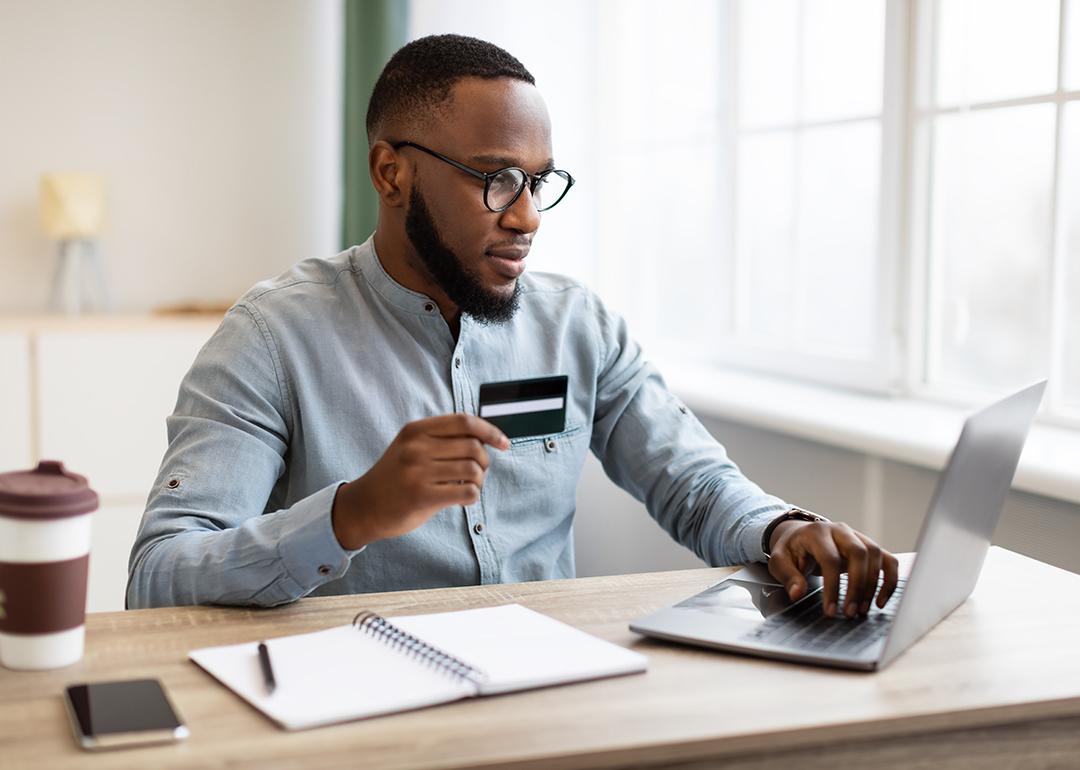 A black businessman using credit card to purchase online while in the office.