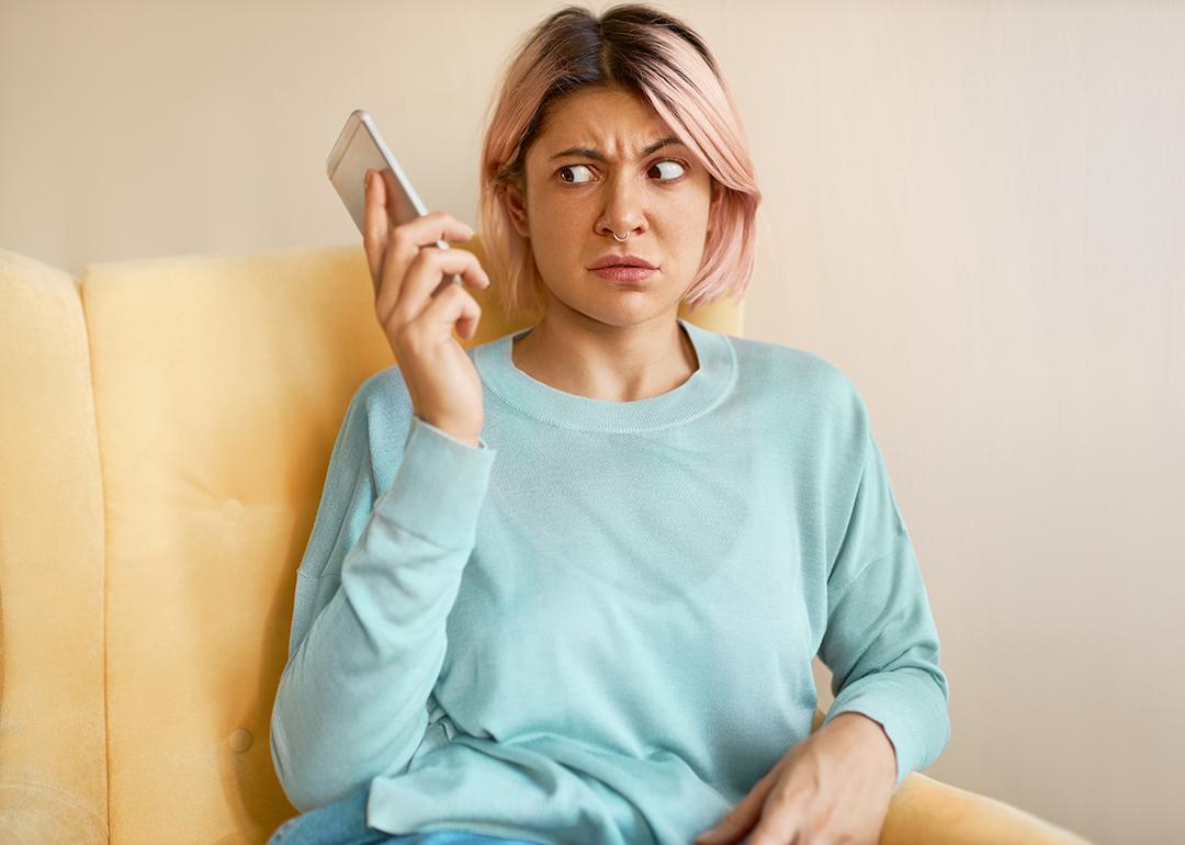 An annoyed woman holding her smartphone due to an unexpected call.
