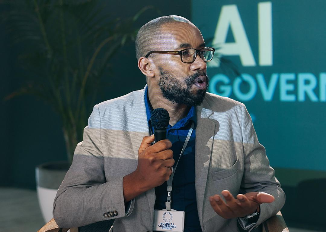 A black businessman giving a presentation on AI governance in a conference.
