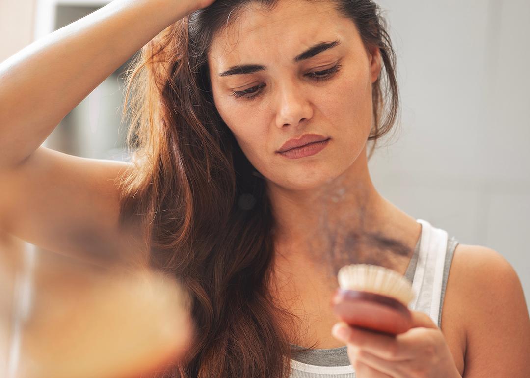 A woman staring at hair loss accumulated in her hairbrush.