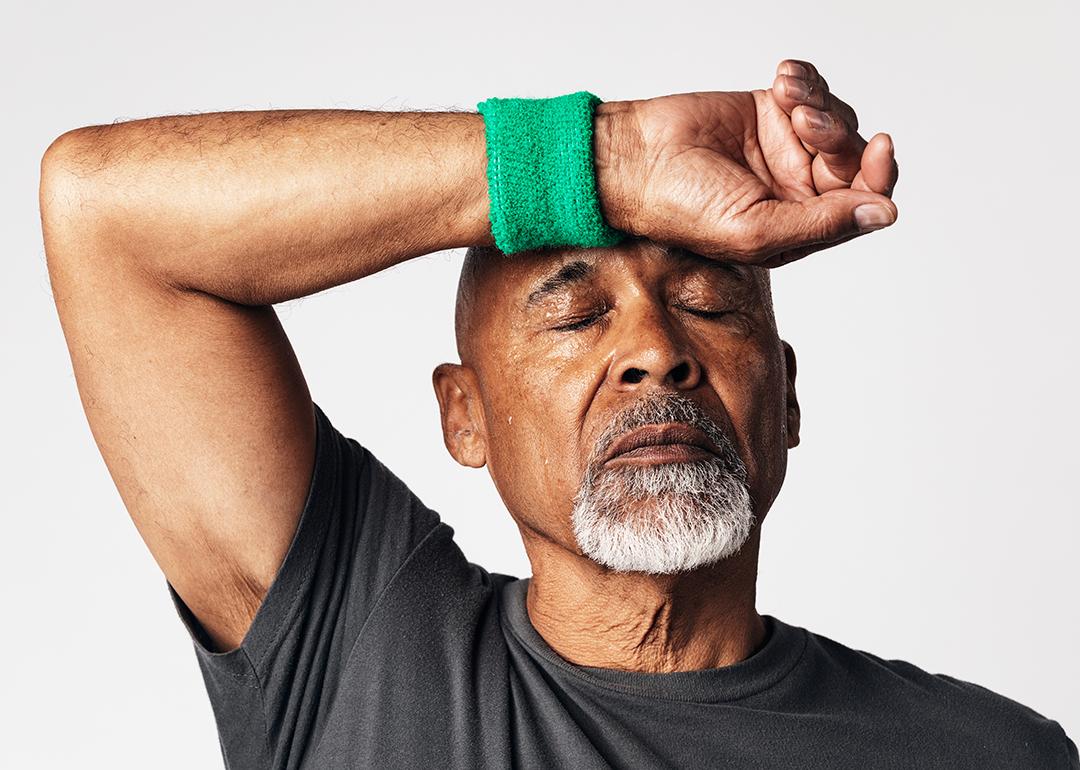 A senior black man wiping off sweat from his forehead.