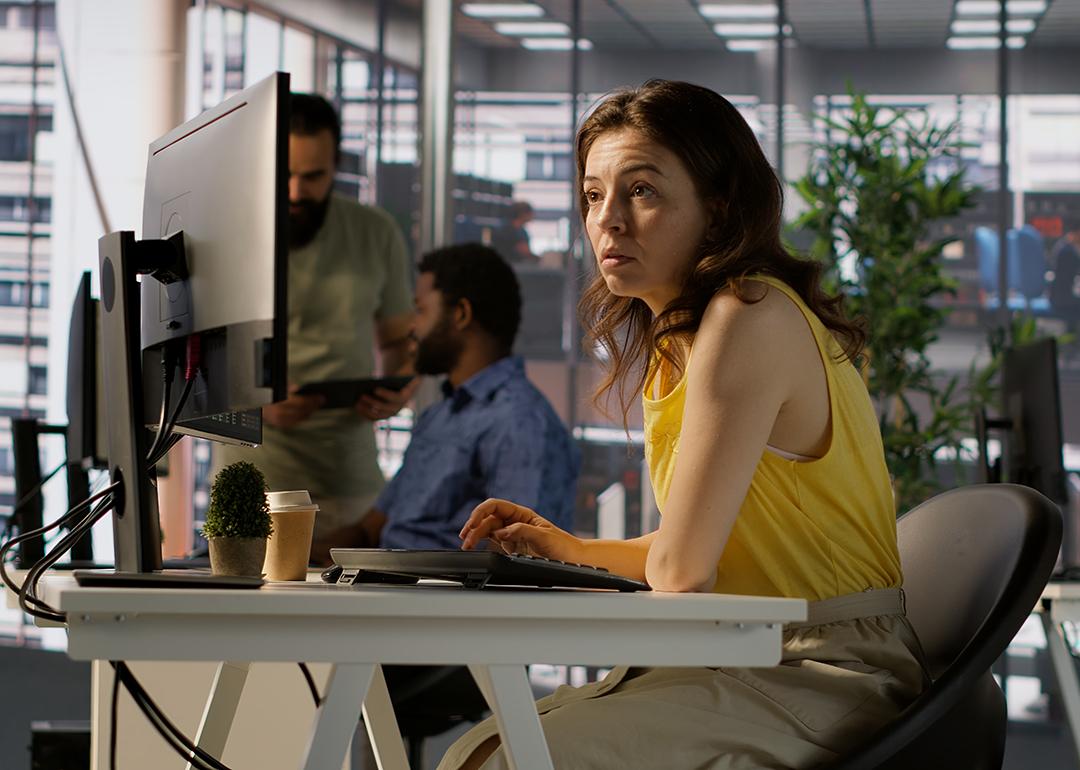  A female employee focused on a computer monitor while working in an office.