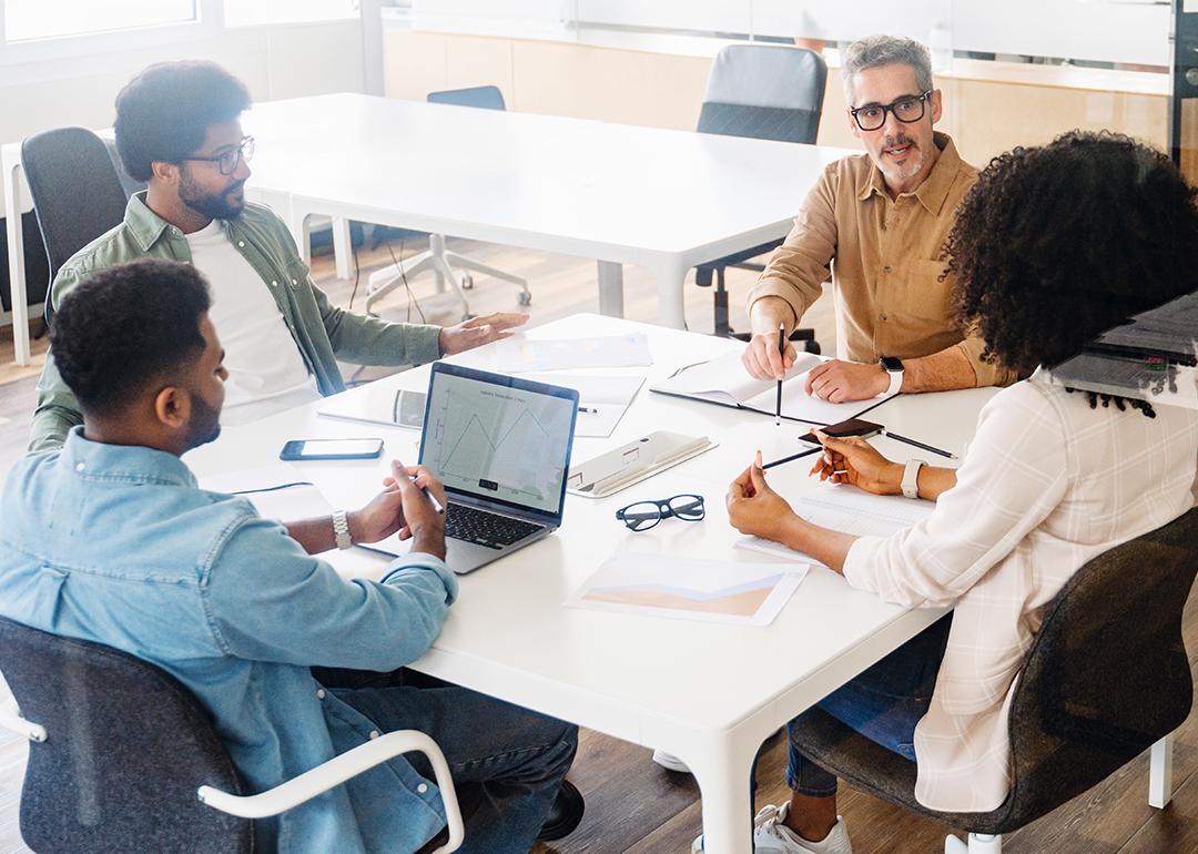 Four members of a business team engaged in a project discussion around a table.