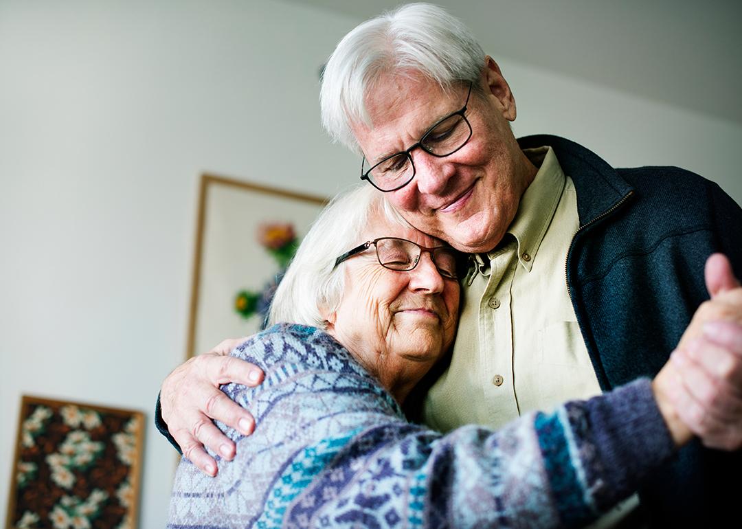 A senior couple dancing together in their home.