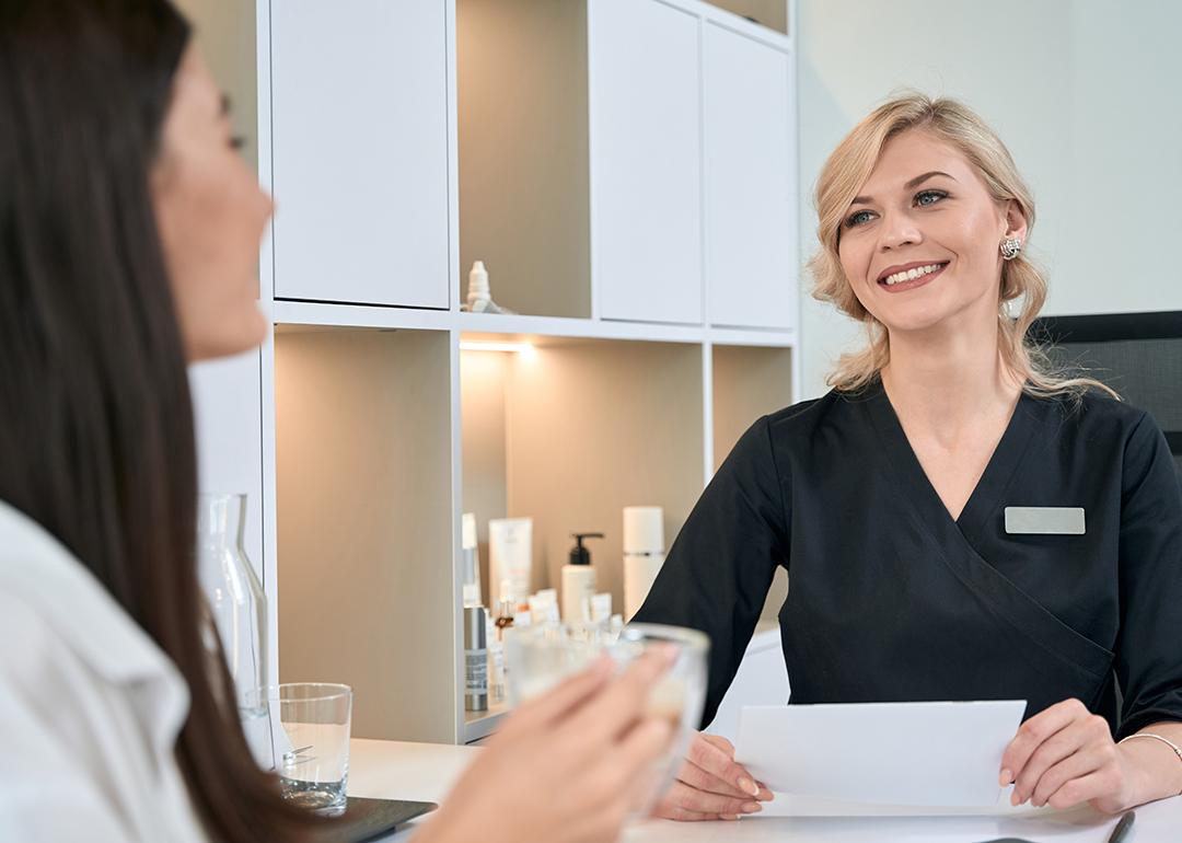A young woman consulting with a dermatologist at the reception bar of a spa.