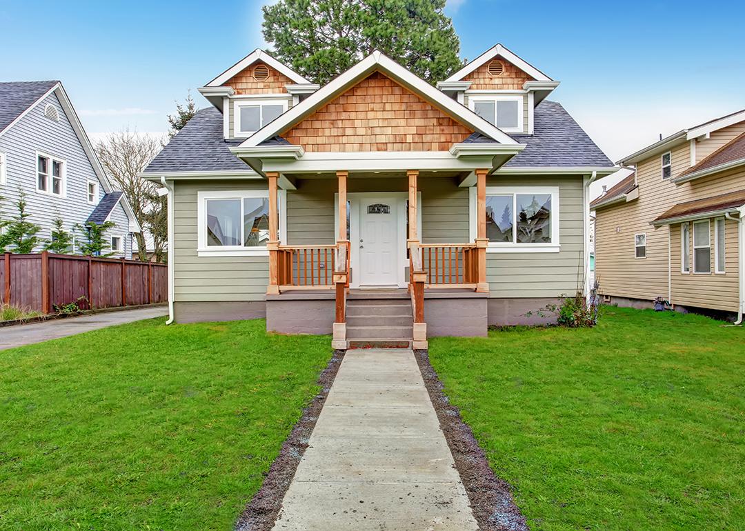 View of a walkway leading to a small house with a porch.