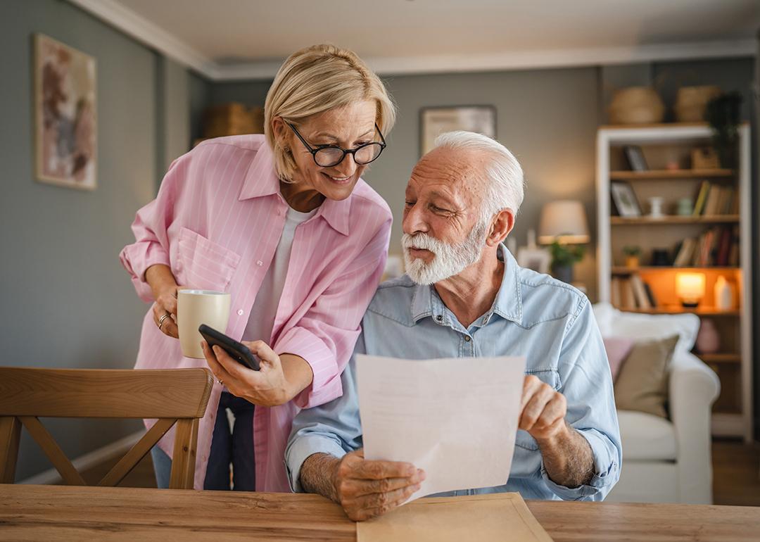 A senior couple reading a document and checking information online together.