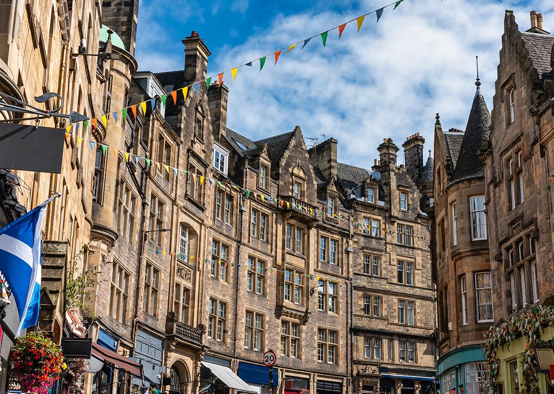 The Old Town street in Edinburgh, Scotland with colorful shops and old stone buildings.