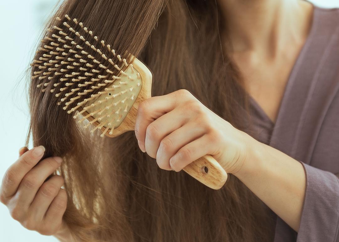 Woman brushing her long hair with a paddle brush.