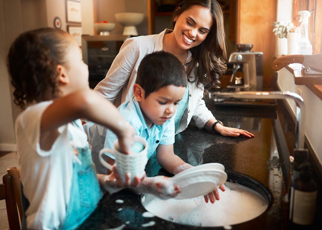 A mother with her two children washing dishes in the kitchen.