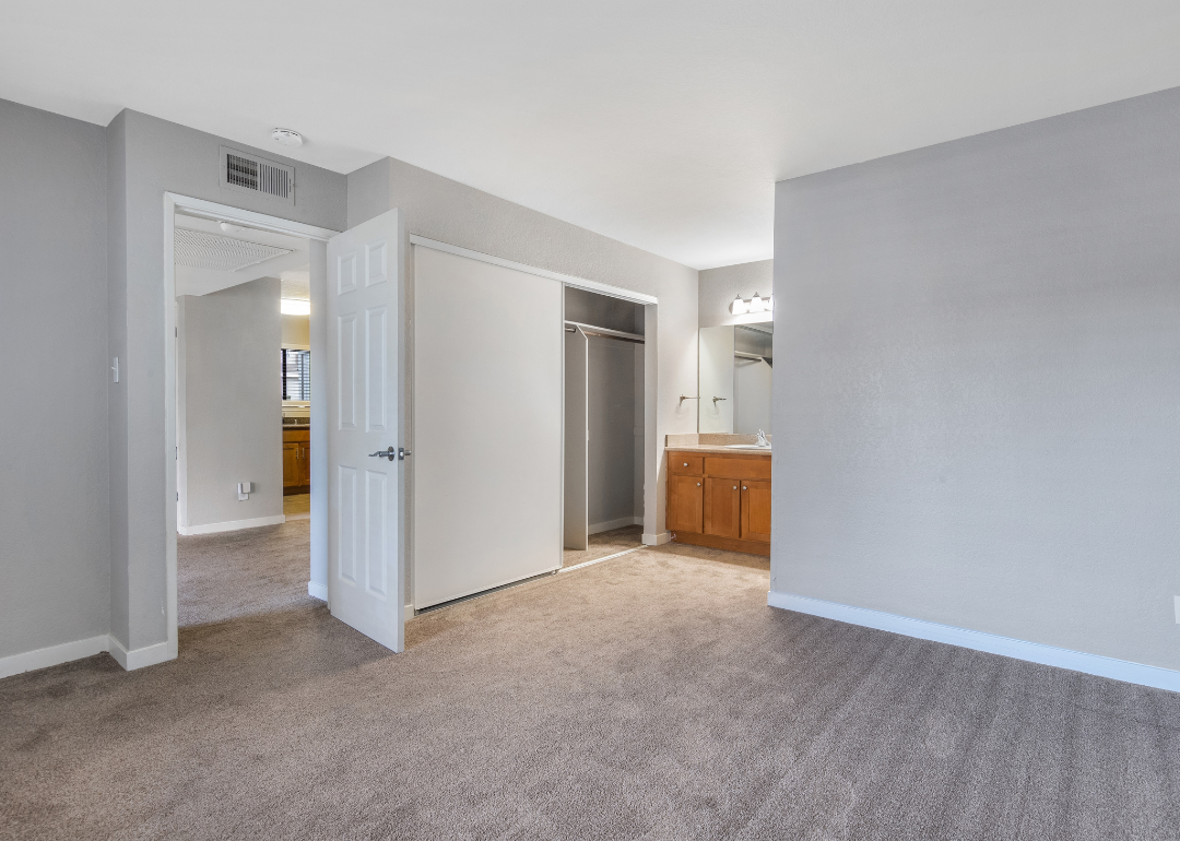 Interior views of an unfurnished apartment unit featuring carpeted bedrooms, built-in vanities, and a gray wall color.