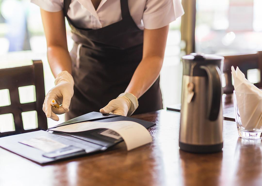 A restaurant waiter collecting the bill from a customer's table.