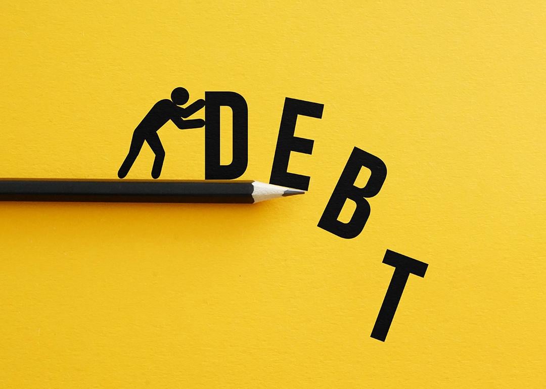 Man pushing away figures of the letters "D, E, B, T" as a concept of relieving debt.
