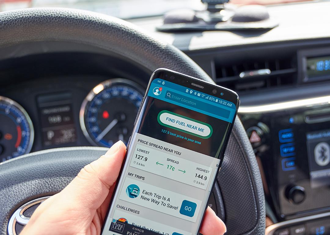 A 'find fuel near me' app displayed on a driver's smartphone while inside the car.