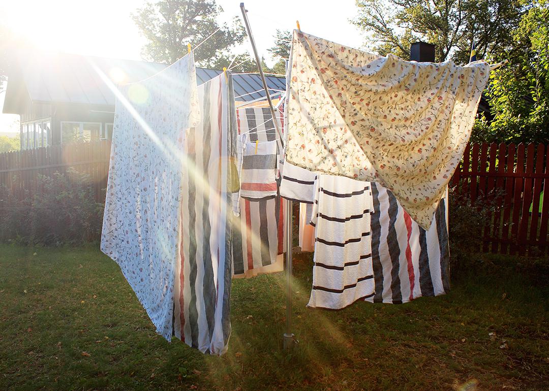 Washed sheets hanging from clothesline to dry under the sun.