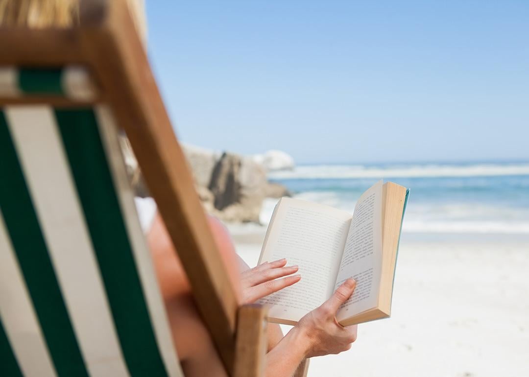 A woman reading a book at the beach.